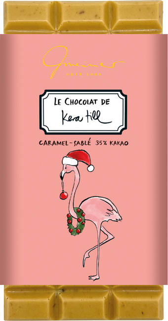 Gmeiner Kera Till Christmas Flamingo Schokolade in rosafarbener Verpackung mit Flamingo, roter Zipfelmütze, Weihnachtskugel im Schnabel und Adventskranz.