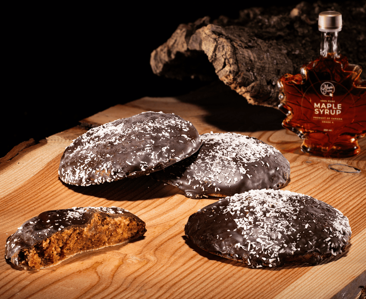 veganer Lebkuchen Düll, Feinkost Schmitz auf einem Holzbrett mit Ahorn Sirup im HIntergrund
